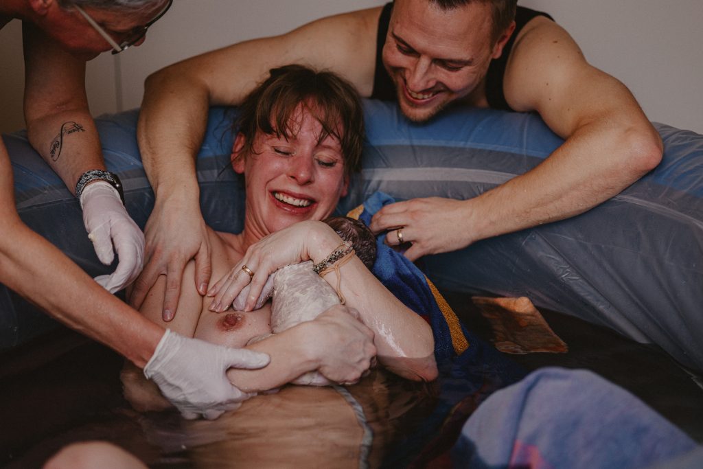 Frau hält zum ersten Mal Baby in Arm Geburtsfotografie Shalynn Crawford Tübingen